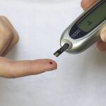 Photo of a person administering a blood sugar test on their finger.