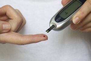 Photo of a person administering a blood sugar test on their finger.